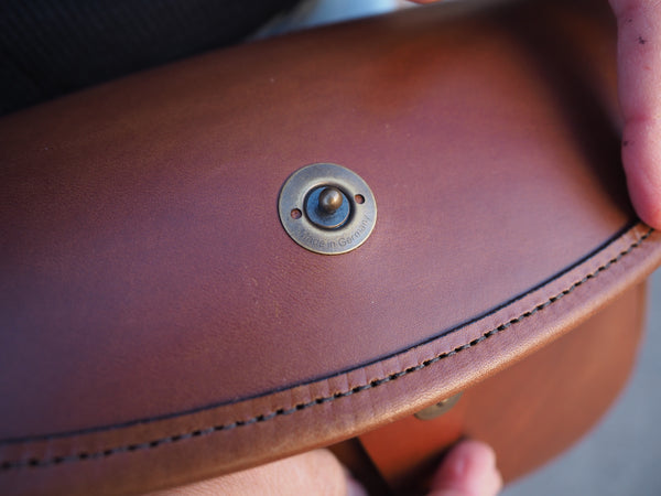 Flap of purse in Medium brown leather and leather binding with solid brass quick release snap.