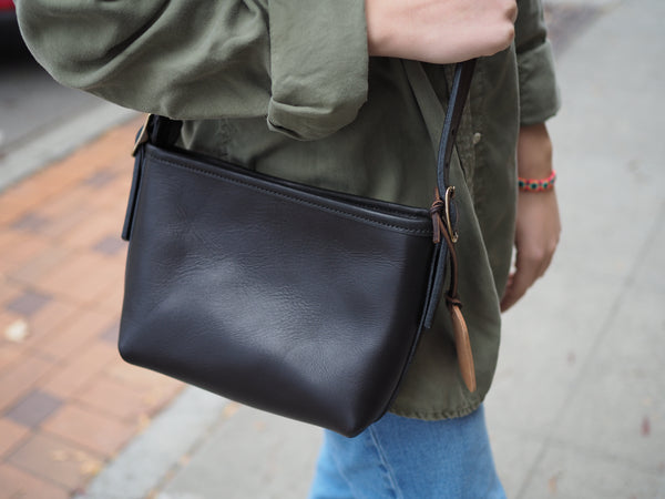 Black leather purse measuring 10 inch width,  6 inch tall, 2.25 inch Deep.  Rounded brass buckles.