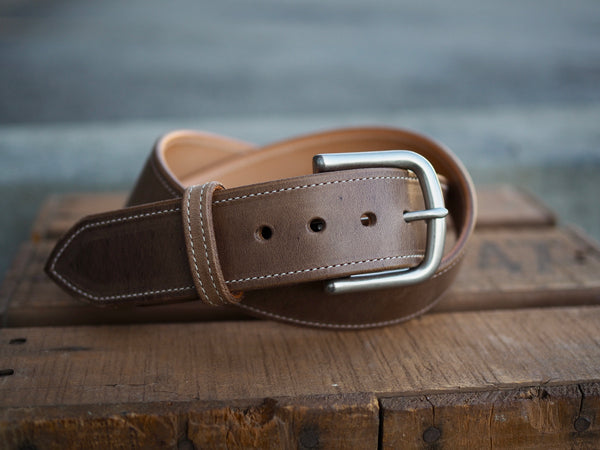 Light brown leather belt with white border stitch and rounded matte nickel buckle.
