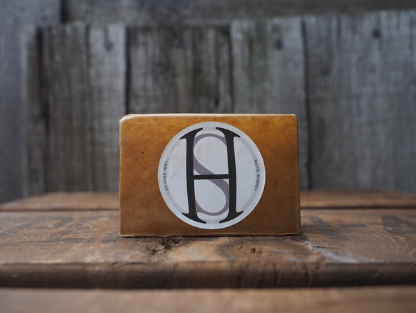 Fabric waxed bar wrapped in brown waxed paper with white circular label 